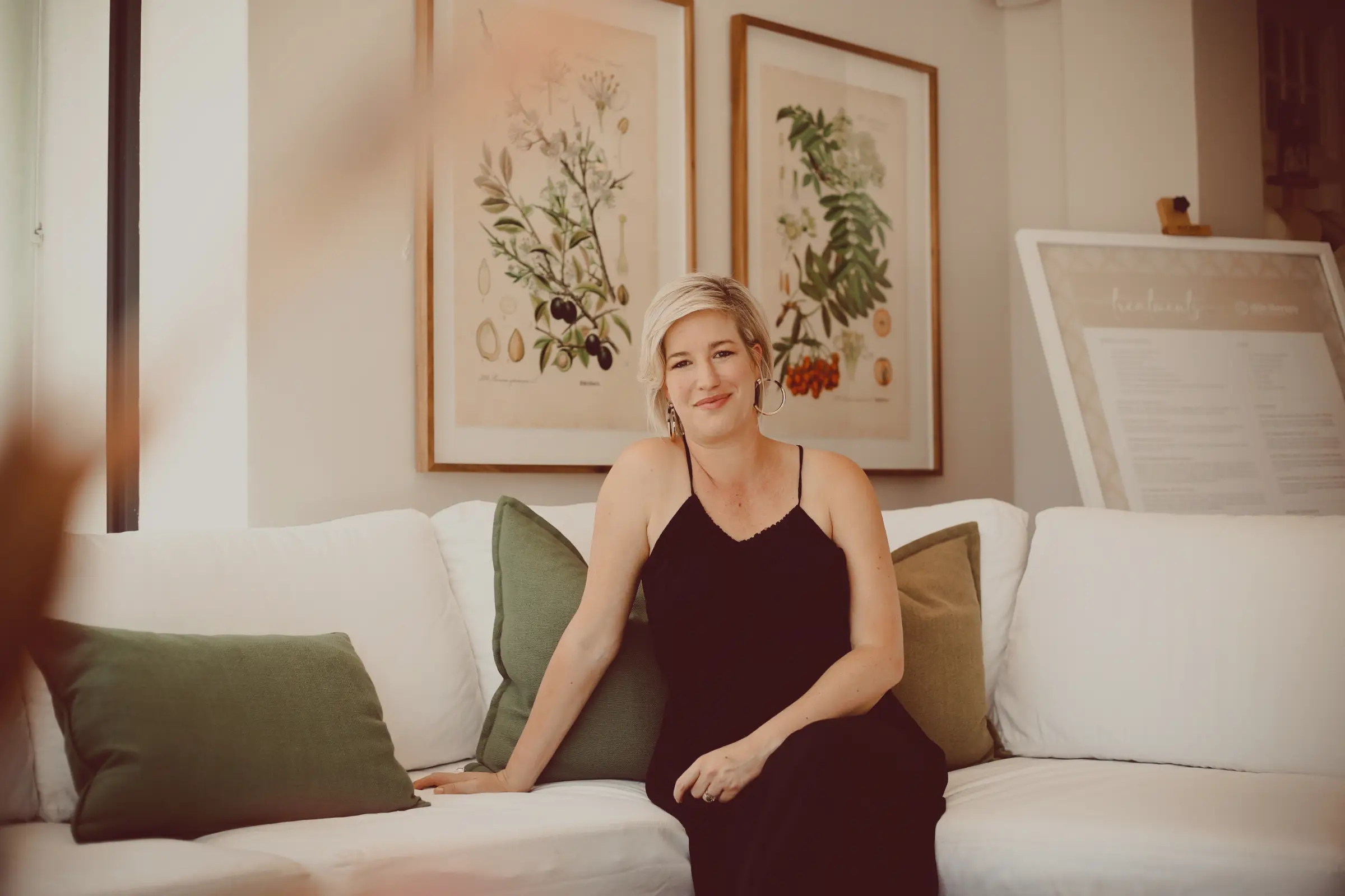 Liesl posing on a couch for a portrait wearing a black dress.